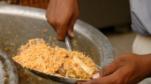 Scooping out a plate of biryani from a pot that’s been cooking all the time.