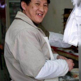 Smiling dumpling seller at a small shop in Beijing, China.